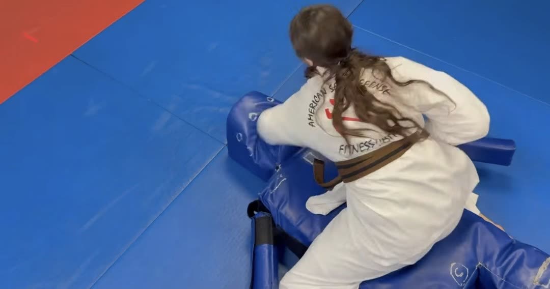Student practicing a defensive technique on the training dummy